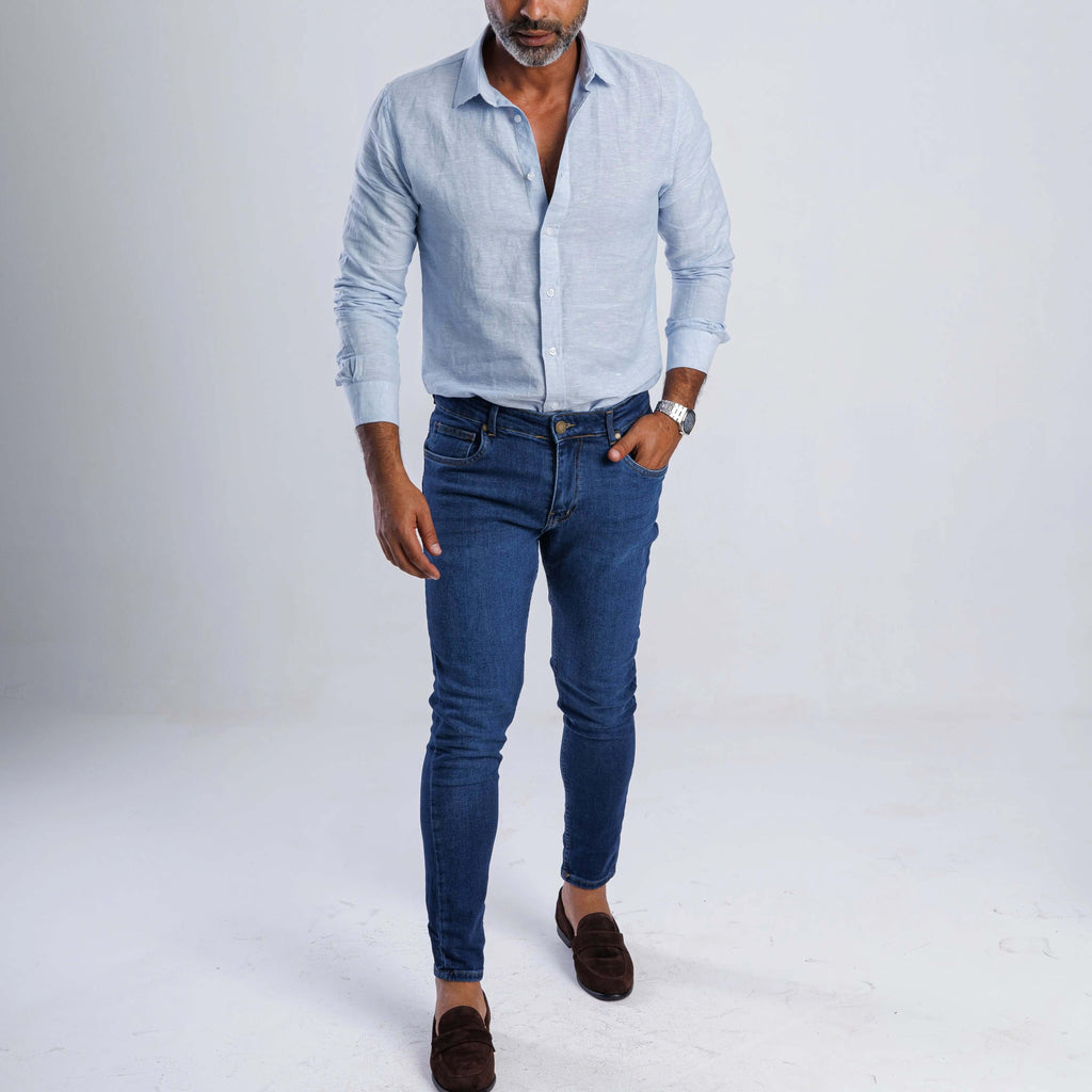 Man wearing a lightweight linen blend slim-fit shirt with long sleeves and blue jeans, showcasing casual summer style.