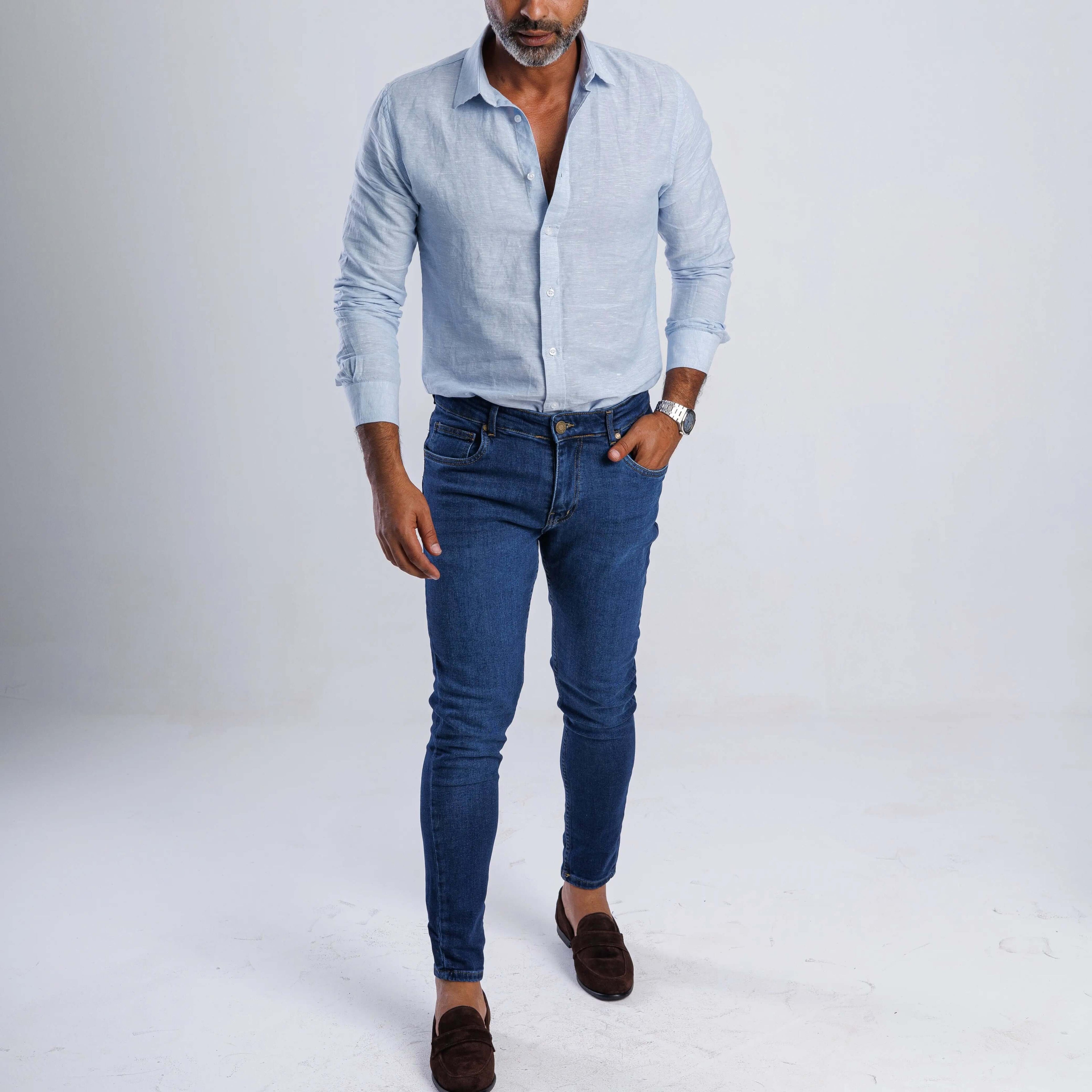 Man wearing a lightweight linen blend slim-fit shirt with long sleeves and blue jeans, showcasing casual summer style.