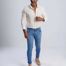 Load image into Gallery viewer, Man wearing a Linen Blend Slim Fit Shirt in beige and blue jeans, showcasing a stylish, casual summer outfit.
