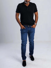 Load image into Gallery viewer, Man in black polo shirt wearing Slim-Straight Flex Denim jeans, showcasing modern style and comfort.
