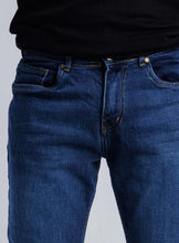 Load image into Gallery viewer, Close-up of solid blue Slim-Straight Flex Denim jeans, highlighting tailored design and quality fabric for comfort and style.
