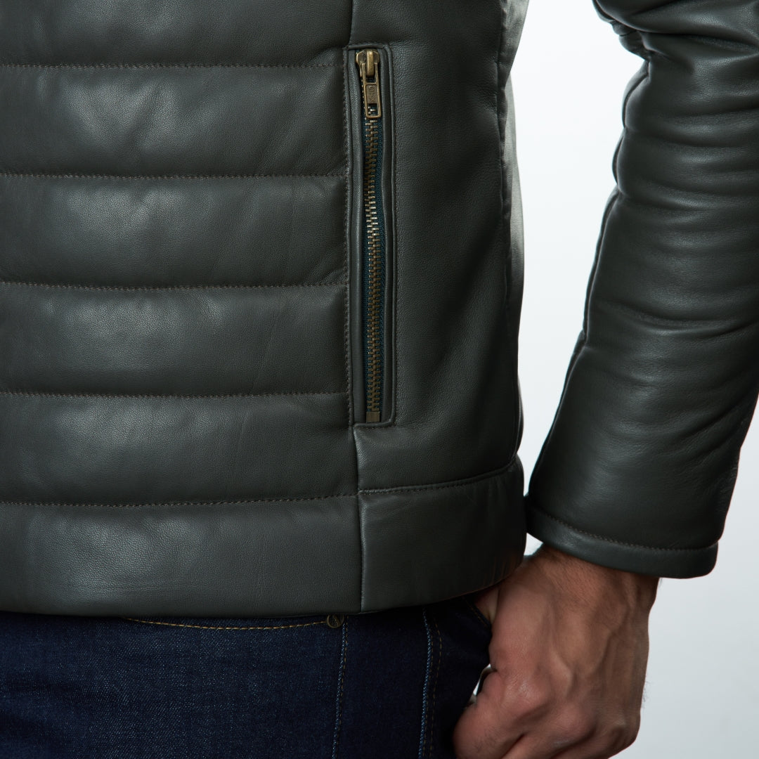 Close-up of a person wearing olive leather jacket with a zipper on a light gray background