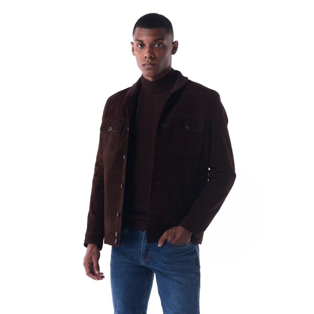 Man wearing a brown jacket over a turtleneck and blue jeans on a white background
