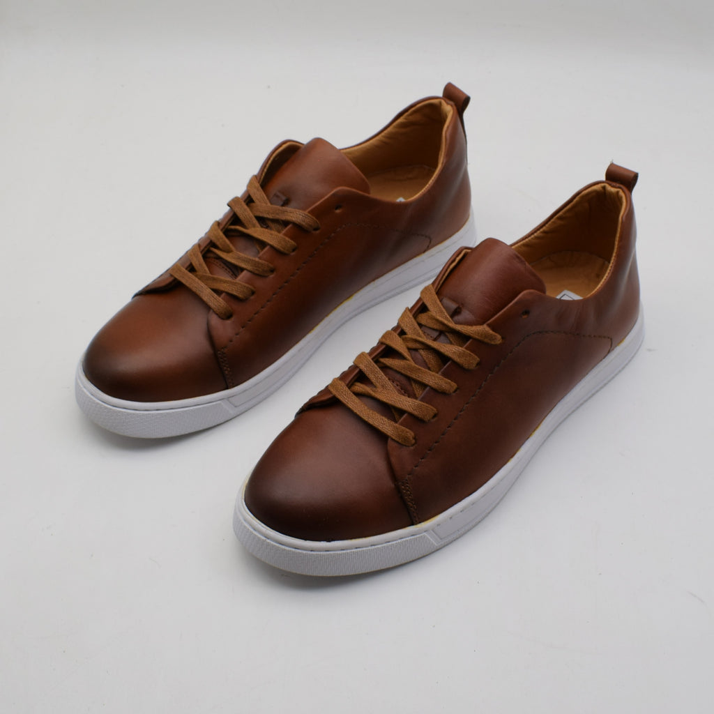 Pair of brown leather sneakers on a light gray background