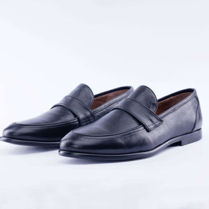 Pair of black leather loafers on a light gray background