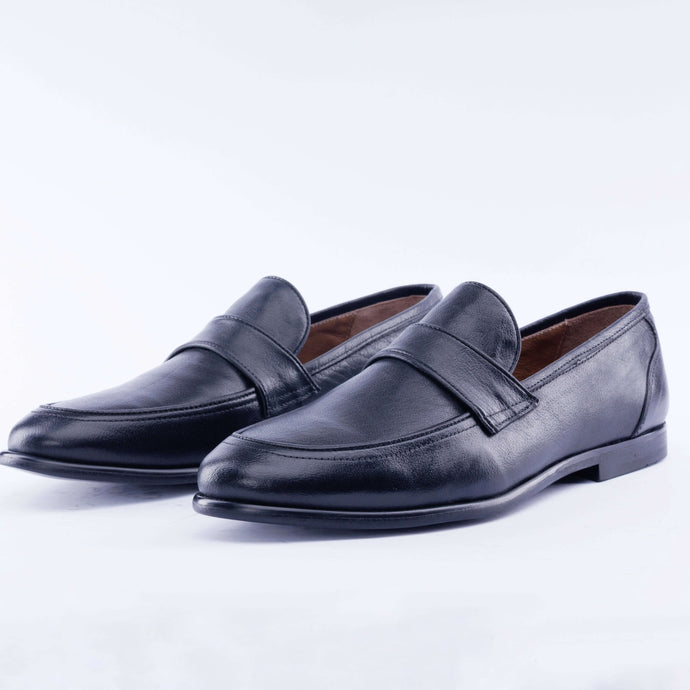 Pair of black leather loafers on a light gray background