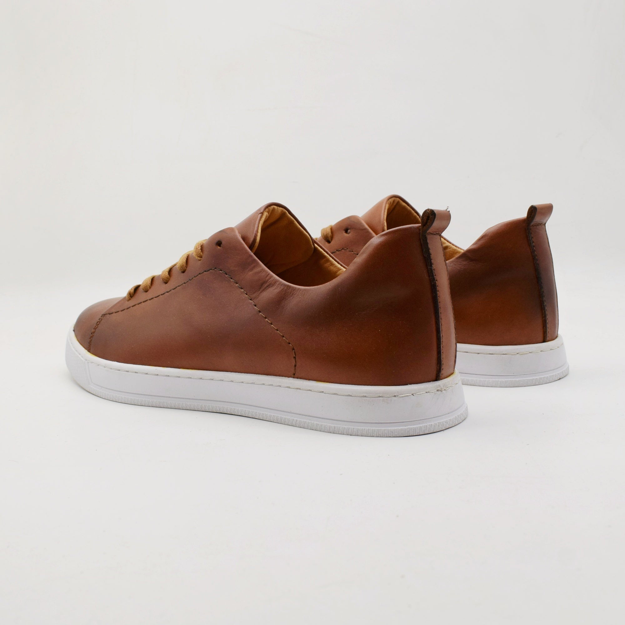 Brown leather sneakers with white soles on a light gray background