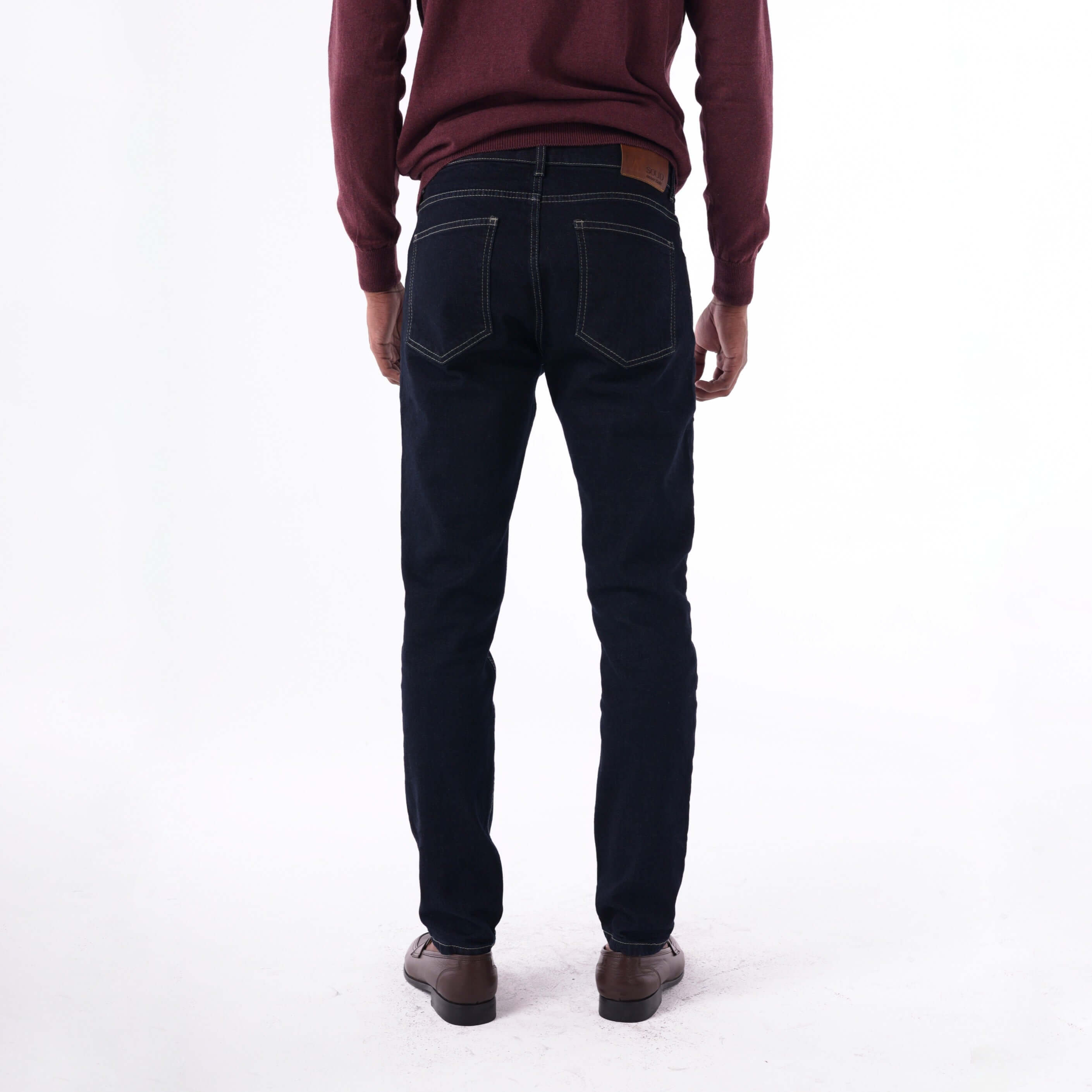 Rear view of a man wearing SOLID navy slim denim jeans with beige contrast stitching.