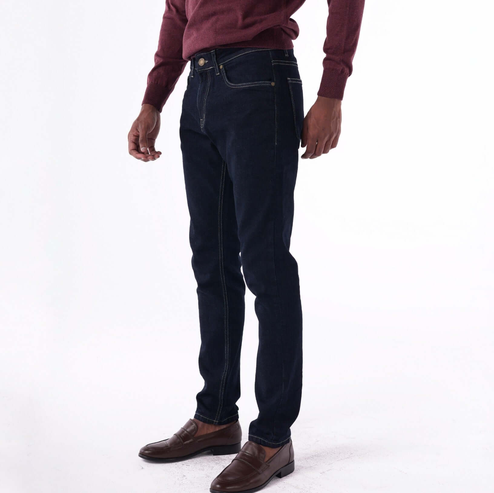 Navy slim denim jeans with contrast stitching, styled with a maroon sweater and brown shoes.