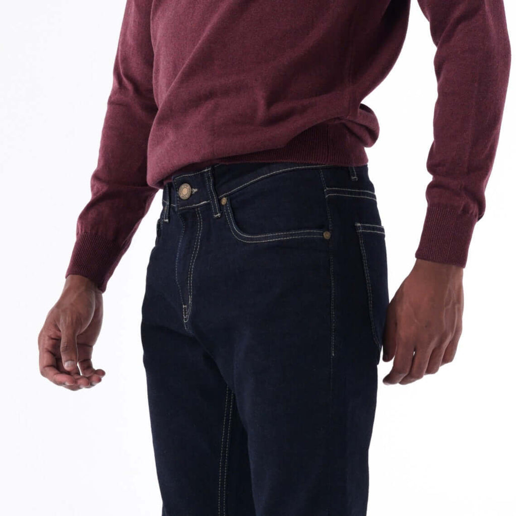 Model showcasing SOLID Navy Slim Denim with beige contrast stitching, paired with a maroon sweater.