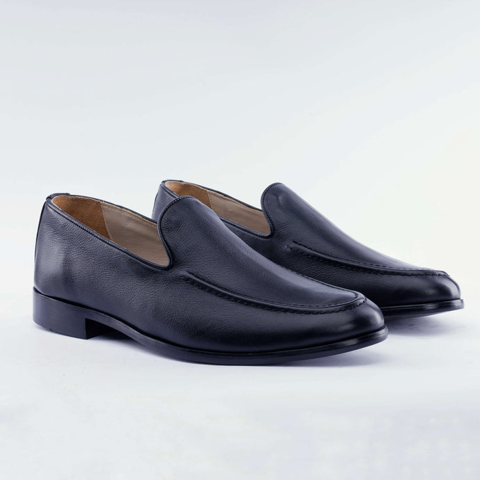 Pair of black leather loafers on a light gray background
