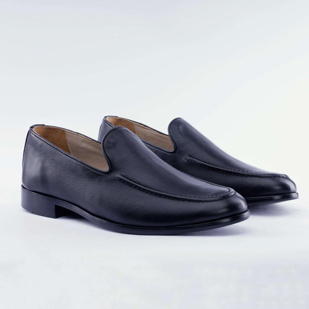 Pair of black leather loafers on a light gray background